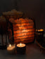 Himalayan salt lamp emitting a warm glow with candles and a decorative item in the foreground.